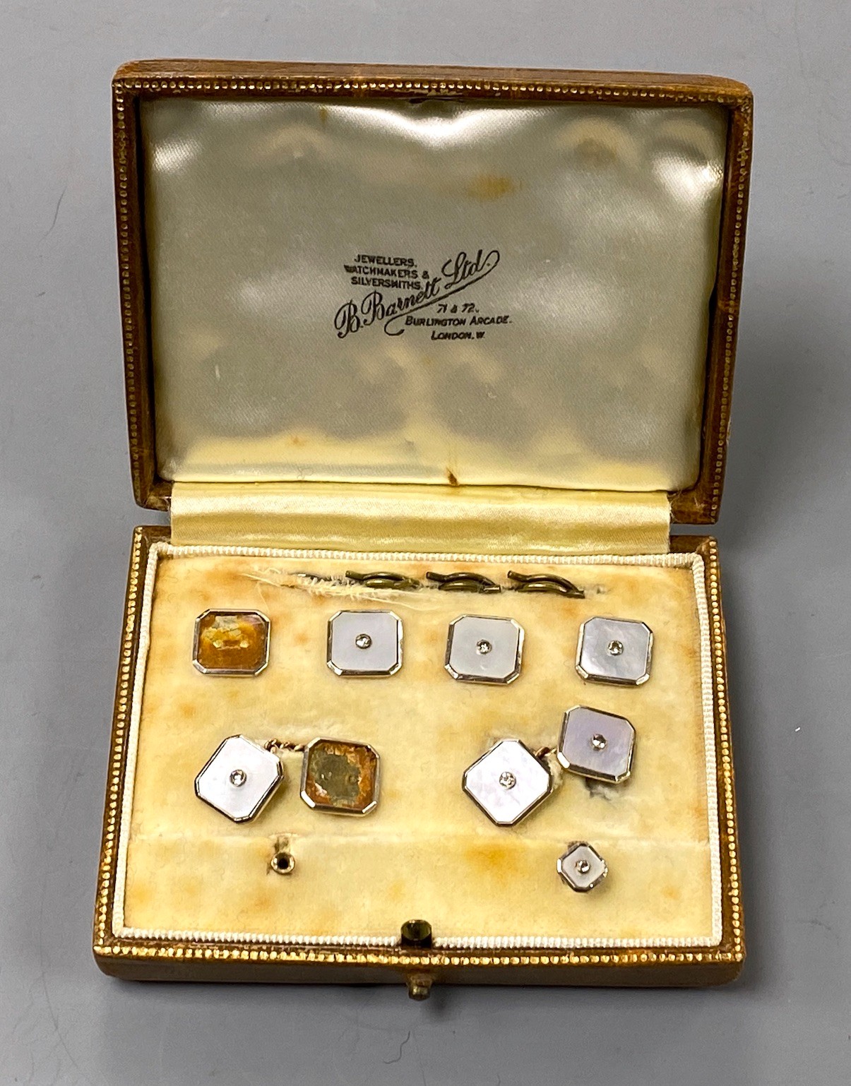 An early to mid 20th century part set 0f 18ct 7 9ct, mother of pearl and diamond set octagonal dress stud set (a.f.), in fitted gilt tooled leather case.